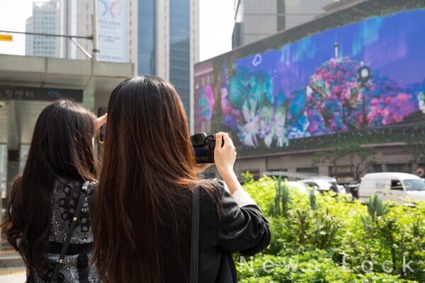 오는 11월 30일까지 명동 신세계 백화점 미디어월(신세계스퀘어)에서 공개되는 아트코리아랩  전시에서 시민과 관람객이 안종훈, 오지연 작가의 3D 아나모픽 미디어아트 작품 ‘다다명동(DaDa Myeongdong)’을 관람하고 있다.